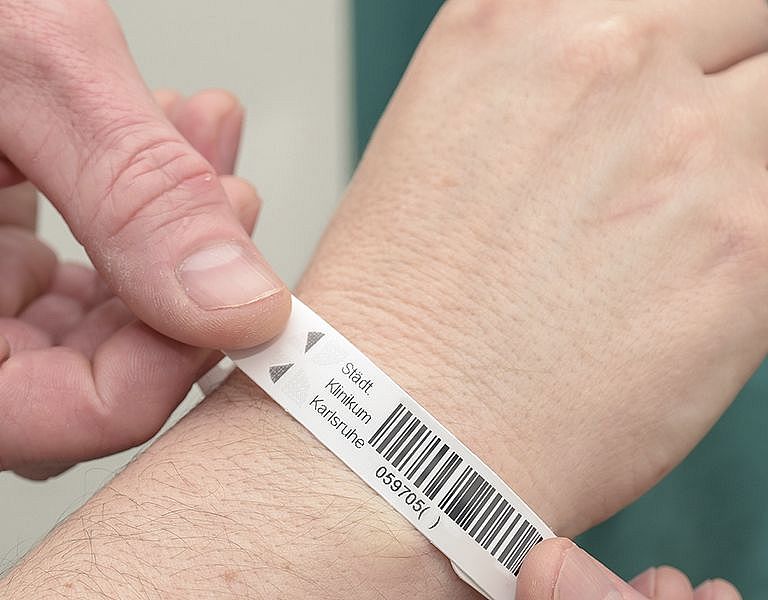 Das Bild zeigt das Anlegen eines Patientenarmbandes
