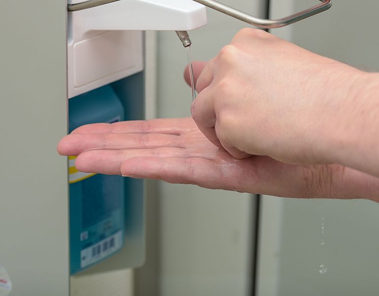 Das Foto zeigt zwei Hände unter einem Desinfektionsspender.