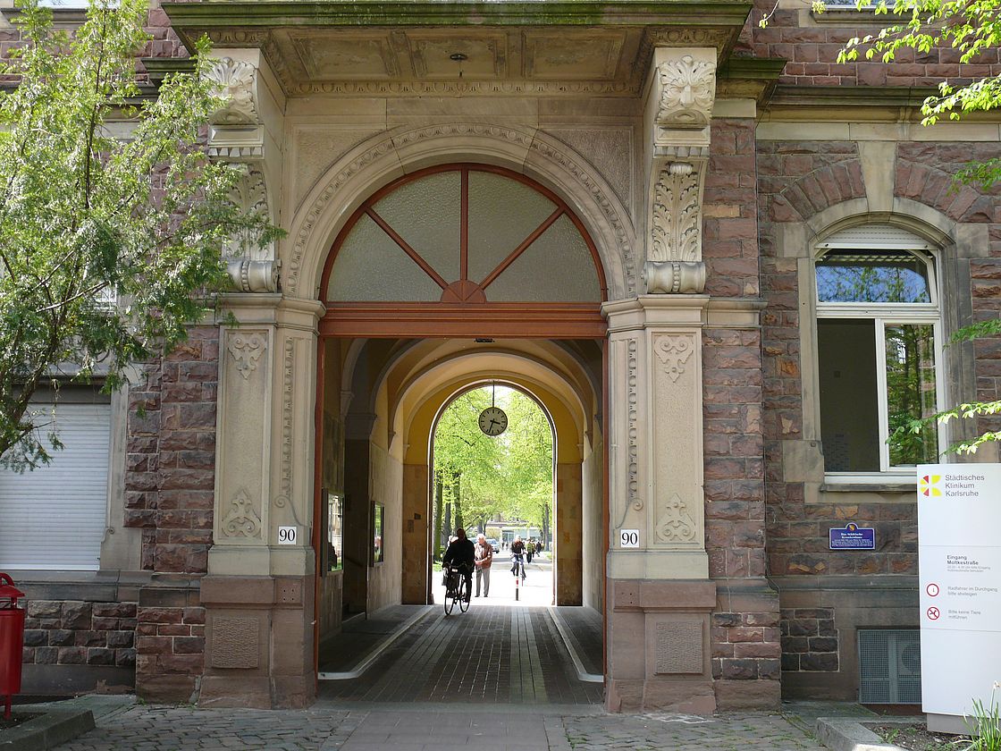 Das Bild zeigt den Zugang auf den Klinikcampus durch den Torbogen von Haus A.